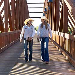 students in cowboy hats walking on a bridge